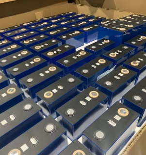 Rows of blue prismatic LiFePO4 battery cells packed neatly in a factory cardboard box for wholesale