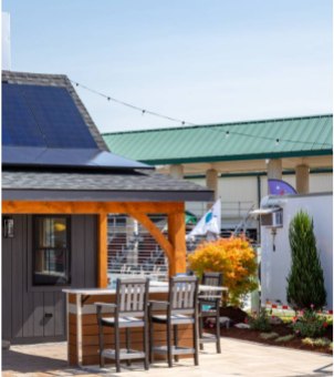 A modern commercial small business building featuring roof-mounted solar panels above an outdoor patio seating area, demonstrating clean energy solutions for retail shops.