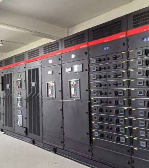 This is a real-world indoor photograph of a modular power conversion system cabinet array. The main subject is a row of large, dark-black industrial electrical distribution cabinets standing side-by-side, extending neatly. A striking bright red horizontal decorative strip adorns the top of each cabinet, above which are large, mesh-like ventilation vents. The cabinet array is divided into different functional areas from right to left: the two cabinets on the right employ a high-density modular drawer-style structure, vertically stacking more than twenty identical small power supply units. Each unit has a rotary black physical switch knob on the left and a miniature LCD data monitoring screen on the right, illuminated with a blue-green backlight. The cabinets in the middle feature large, enclosed black metal doors, inlaid with a medium-sized LCD monitoring display, square buttons, and red emergency shut-off or indicator handles. The cabinets on the left have vertically grilled, perforated ventilation doors. The entire server room floor is a gray-white hardened cement floor or anti-static floor, with white architectural ceiling beams visible above. The image, taken from a side angle, showcases the professional, rigorous, and high-tech hardware deployment of the data center's core power room.