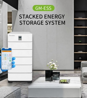 This digitally-driven promotional poster, designed for marketing new energy products, showcases GreenMore's GM-ESS Stacked Energy Storage System. The background is a modern living room with a sophisticated, understated luxury feel. On the right is a long, multi-tiered black display shelf, behind which is a light gray marble-textured art wall with vertical slits. Above this is a capsule-shaped logo in white lettering on a green background: 'GM-ESS', followed by two lines of bold black capital letters: 'STACKED ENERGY STORAGE SYSTEM'. In the mid-ground on the left, a pure white rectangular stacked energy storage battery cabinet, designed specifically for home use, stands. The upper left corner of the cabinet features a green 'GreenMore' brand logo, and the top layer houses a small digital LCD control panel and buttons. Below, multiple battery modules are vertically and tightly stacked on a black load-bearing base. In the foreground on the left side of the front of the server rack, a hand wearing a bright blue protective glove holds a white-rimmed smartphone. The screen displays a user interface for a green energy smart management app, featuring an orange top bar, multiple light-colored data monitoring dashboards (such as various electrical parameters and setting icons), and a dynamic topology diagram of power flow below. Extending from the bottom of the image is a rectangular marble coffee table with light gray natural textures. On the table sits a delicate black vase holding several small white flowers. Next to the vase is a gray plate containing a few green apples. The edge of a high-end gray fabric sofa is faintly visible on the right. The poster's layout is clear and well-organized, seamlessly integrating cutting-edge lithium battery energy storage technology into a warm and comfortable modern smart home setting.