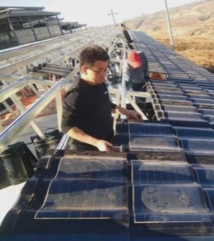 Engineers quickly install GreenMore lightweight solar tiles on the roof support structure.