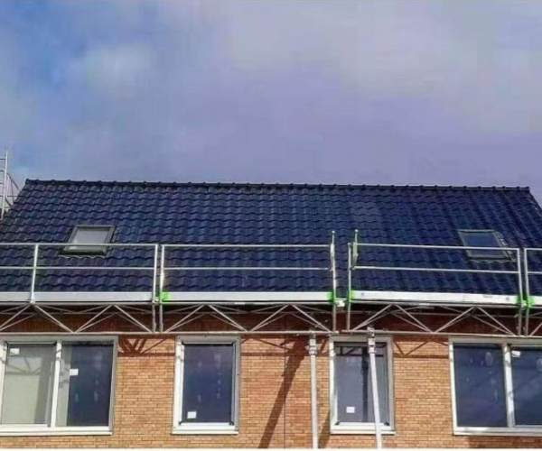 Real-life construction scene of GreenMore brick house roofing covered with dark blue triple-arched solar tiles.