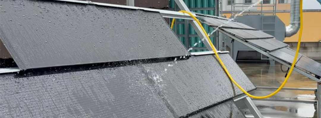 greenmore-solar-roof-tile-waterproof-testing A real-life scene of GreenMore solar tiles undergoing a high-pressure spray waterproofing test on a pitched roof frame.