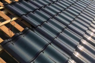 Detailed construction diagram of GreenMore solar tiles being laid on roof battens and connected with cables.