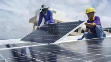 Real-life photos of GreenMore's professional installation team installing photovoltaic solar modules on a building rooftop.