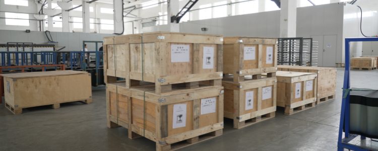 Real-life photos of GreenMore solar tile export crates being packed and stored in a warehouse awaiting shipment.